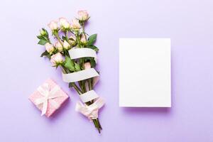 Greeting holiday card mockup with fresh roses on colored table background, mock up with copy space design photo