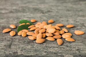 Close-up of Almonds nuts with leaves on table background. Top view. Flat lay photo