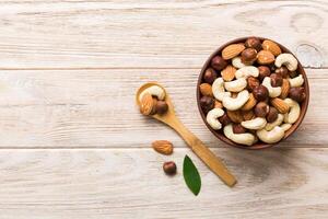 Assortment nuts in wooden bowl colored table. Cashew, hazelnuts, walnuts, almonds. Mix of nuts Top view with copy space photo