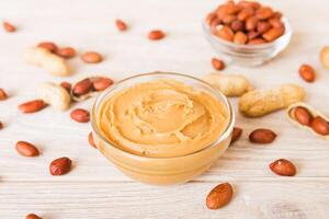 Bowl peanut butter and peanuts on table background. top view with copy space. Creamy peanut pasta small bowl photo