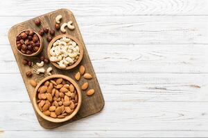 Assortment nuts wooden bowl colored table. Cashew, hazelnuts, walnuts, almonds. Mix of nuts Top view with copy space photo