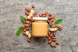 Bowl peanut butter and peanuts table background. top view with copy space. Creamy peanut pasta in small bowl photo