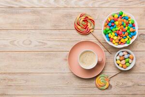 Coffee cup with chocolates and colored candy. Top view table background with copy space photo