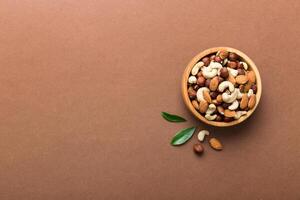 Assortment nuts wooden bowl colored table. Cashew, hazelnuts, walnuts, almonds. Mix nuts Top view with copy space photo