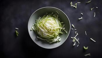 Top down view of fresh cabbage shreds in a ceramic bowl against a black backdrop photo