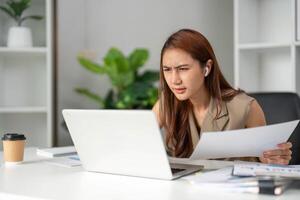 Work Online and Focused Analysis. A young professional shows concentration and determination while analyzing documents at her workstation. photo