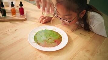 Child closely observes soap and color reaction in plate video