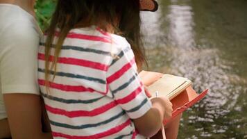 Relaxing by the stream with feet in water and notebook in hand video