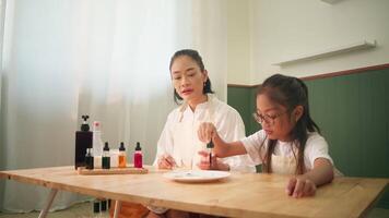 Mother Guiding Daughter Through Science Experiment at Dining Table video