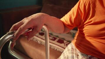 Close up of elderly man's hand gripping walker handle at home video