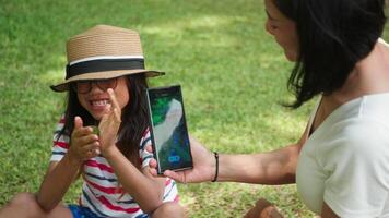 Child showing nature find while mother takes photo with smartphone video