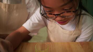 Child focuses while doing surface tension experiment at home video