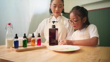 Child Pumping Dish Soap into Small Glass with Parent Preparing for Science Experiment video
