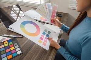 Color Evaluation and Design Creation. An artist analyzing color schemes and refining design elements at her desk. photo