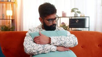 Indian man hugging pillow with sad expression, feeling heartbroken and lonely after bad unlucky day video