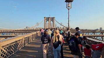 New York. US. 03.03.2025. Brooklyn Bridge pedestrian walkway crowded with tourists and locals, offering stunning views of Manhattan under a clear sky video