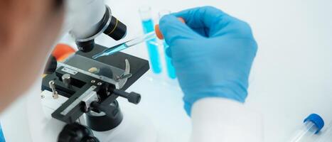 close up Scientist analyze biochemical samples in advanced scientific laboratory. Medical professional use microscope look microbiological developmental of viral. Biotechnology research in science lab photo