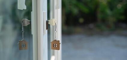 Landlord key for unlocking house is plugged into the door. Second hand house for rent and sale. keychain is blowing in the wind. mortgage for new home, buy, sell, renovate, photo