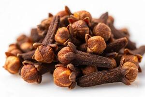 A close up studio shot of a pile of dried brown cloves on a white background for culinary use photo
