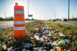 Road maintenance crew in bright vests picking up roadside litter with traffic cone detail photo