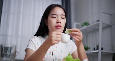 Handheld low angle view shot, Asian woman enjoys delicious salad rolls at the dining table in home. Enjoy healthy food video