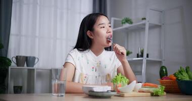 Handheld shot, Beautiful woman enjoys eating fruits at dining table at home. Enjoying healthy food. video