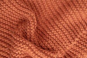 Orange knitted fabric texture abstract background. A slightly crumpled knitted blanket made of woolen threads. Winter or autumn background photo