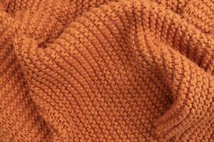 Orange knitted fabric texture abstract background. A slightly crumpled knitted blanket made of woolen threads. Winter or autumn warm background. photo