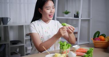 Beautiful Asian woman enjoys delicious salad rolls at the dining table in home. healthy food video