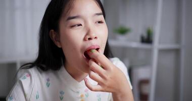 Handheld selective focus shot, Asian woman enjoys delicious salad rolls at the dining table in home. Enjoy healthy food video