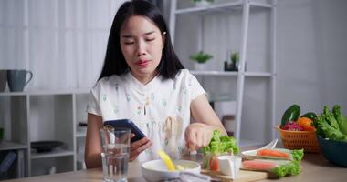 Handheld shot, Beautiful woman enjoys eating fruit while playing with mobile phone happily at home. Relax at home, Enjoy healthy food video