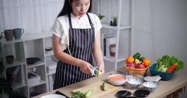 Handheld high angle view shot, Young woman in a striped apron is preparing vegetables for cooking. video