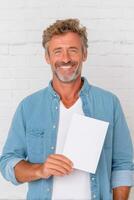 Confident man smiling while holding blank paper in hand, showcasing voting enthusiasm and engagement in democratic process, civic participation concept photo