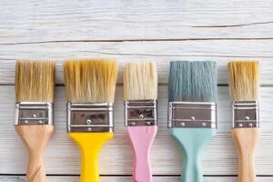 Vibrant collection of paintbrushes arranged in a row showcasing various bristle textures and colors against a rustic wooden background for creative projects photo