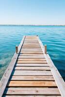 Wooden dock extending over calm blue water under a clear sky, inviting relaxation and tranquility, perfect for nature lovers and outdoor enthusiasts seeking peaceful moments photo