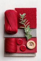 Jester red yarn, fabric swatches, and buttons arranged artistically with greenery, showcasing vibrant textures and colors for creative projects and design inspiration photo