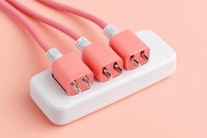 Power strip with three pink electrical outlets and matching cables on a soft pastel background, showcasing modern design and functionality in home or office settings photo