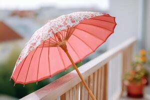 Decorative pink parasol with floral patterns rests on a wooden railing, providing shade and enhancing outdoor ambiance in a serene garden setting with soft colors photo