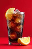 Refreshing glass of cola filled with ice cubes and garnished with lemon slices, set against a vibrant red background, showcasing a thirst-quenching beverage experience photo