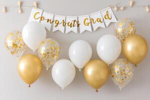 Colorful balloons in white, gold, and confetti designs are arranged with a festive banner reading Congrats Grad, creating a celebratory atmosphere for graduation events photo