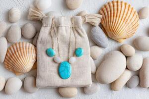 Turquoise jewelry set displayed on a textured surface with seashells and smooth pebbles, showcasing natural beauty and elegance in a serene coastal environment photo