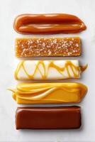 Various caramel textures and colors arranged in horizontal lines on a white surface, showcasing different styles and flavors of this sweet confectionery treat photo