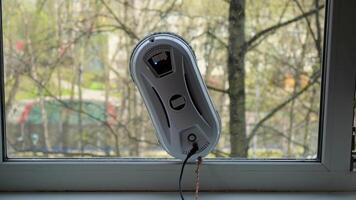 Robotic window cleaner progressing on glass surface in springtime setting video