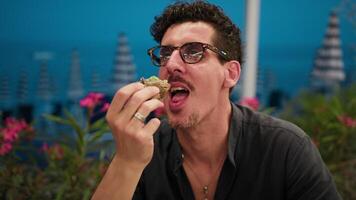 Man Eating A Burger And Smiling At The Resort With Sea Background video