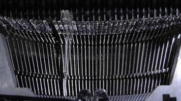 Letters hitting the paper while typing in an old qwerty typewriter video