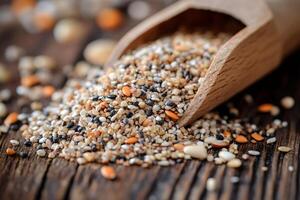 Mixed seeds spilling from wooden scoop on rustic table photo