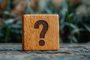 Question mark engraved on wooden block on rustic surface photo