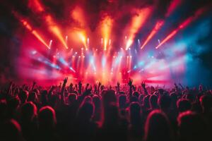 Crowd cheering and raising hands at illuminated concert with red and blue lights photo