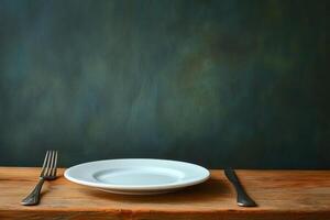 Empty white plate with fork and knife on wooden table and green background photo