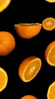 Oranges float down beautifully against a deep black background in slow motion. video
